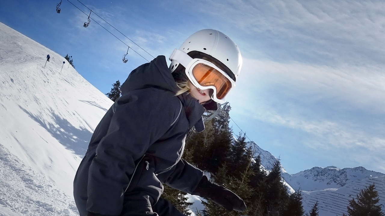 Enfant faisant du snowboard sur une montagne enneigée.