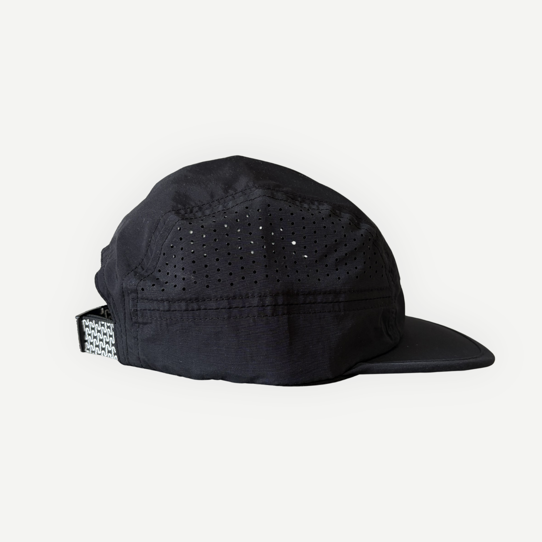 Casquette de course en nylon noire de la marque Périple avec panneaux perforés favorisant la respirabilité, vue latérale gauche.