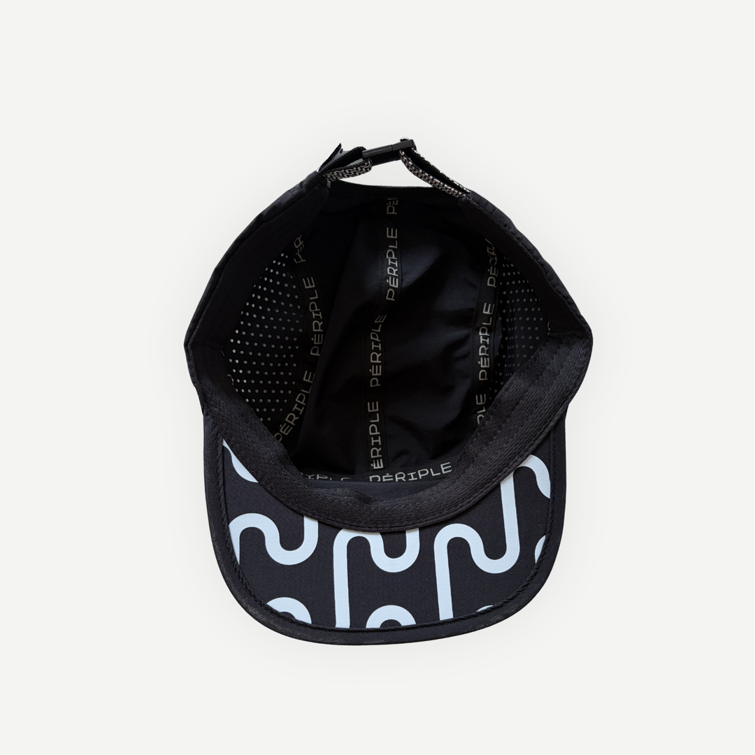 Vue intérieure de la casquette de course en nylon noire de la marque Périple montrant les panneaux perforés, les bandes de finition et le dessous de la visière à motif graphique.