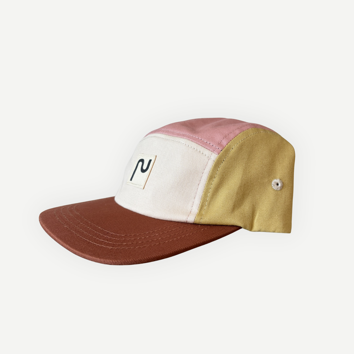 Casquette en coton à 5 panneaux de la marque Périple. Modèle colorblock lila, rose, jaune moutarde et crème avec visière brun cacao, vue latérale droite.