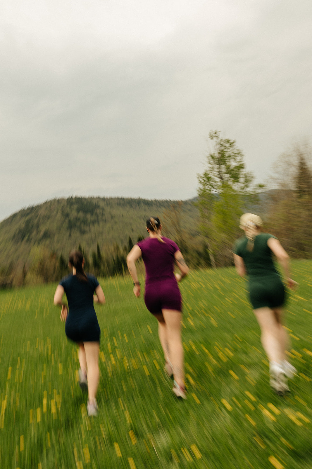 Trois femmes profitent d'une sortie active en plein air dans les montagnes en portant les biker shorts et t-shirt col v marine de la collection Activmom x Périple (à gauche) ainsi que pourpre (au milieu) et Émeraude (à droite).