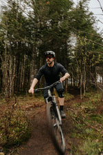 Homme en descente de vélo de montagne portant le chandail à manches longues en laine de mérinos ardoise de Périple. 