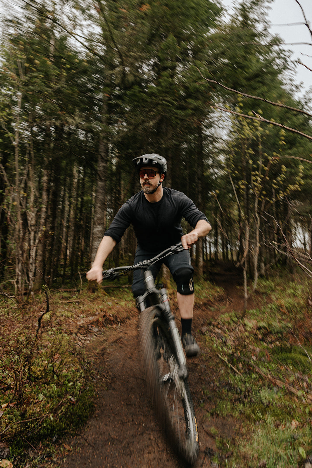 Homme en descente de vélo de montagne portant le chandail à manches longues en laine de mérinos ardoise de Périple. 