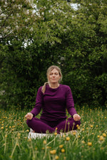 Femme portant un chandail à manches longues et un legging en laine de mérinos Pourpre de Périple lors d'une séance de yoga en plein air.