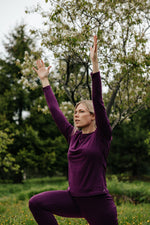 Femme portant un chandail à manches longues et un legging en laine de mérinos Pourpre lors d'une séance de yoga en plein air.