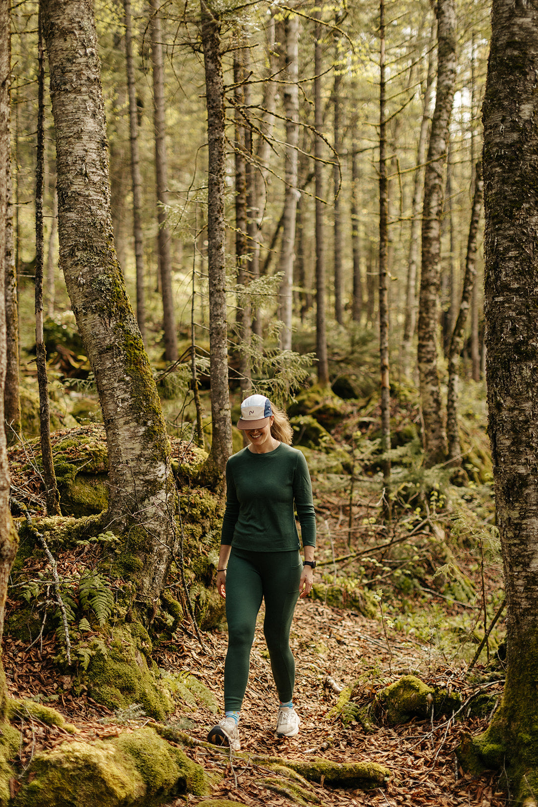 Ensemble en laine de mérinos Émeraude pour femmes de Périple composé d'un chandail manches longues et d'un legging lors d'une randonnée en forêt.